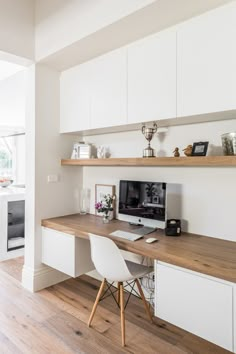 a desk with a computer on top of it in front of a wall mounted shelf