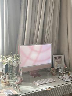 a desktop computer sitting on top of a desk in front of a window with curtains