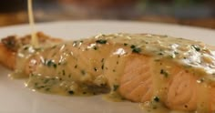 a piece of salmon covered in gravy on a white plate