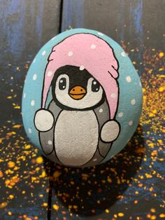 a painted rock with a penguin wearing a pink hat