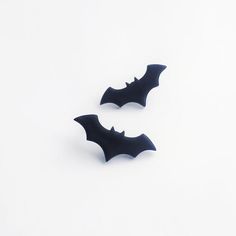 two black bats sitting on top of a white table next to each other and one is upside down