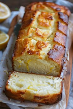 a loaf of lemon bread sitting on top of a cutting board next to sliced lemons