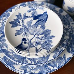 blue and white plates with birds on them sitting on a wooden table next to each other