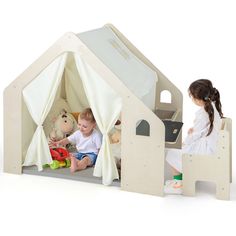 two children playing in a play tent with stuffed animals on the floor and one child holding a teddy bear