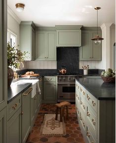 a kitchen with green cabinets and black counter tops