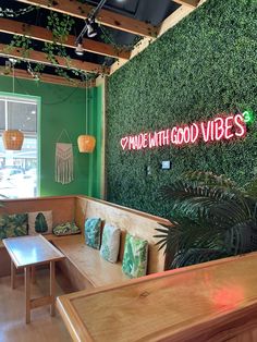 the inside of a restaurant with green walls and plants on the wall behind the booth