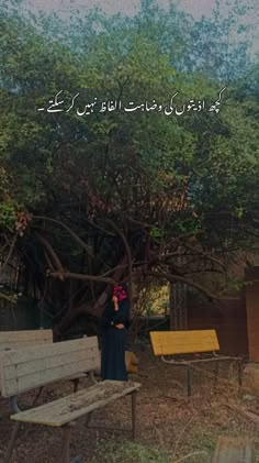 a woman standing next to a wooden bench in front of a tree with writing on it