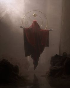 a person in a red robe is suspended upside down from the ceiling with a ring around their neck