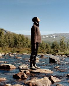 a man standing on rocks in the middle of a river