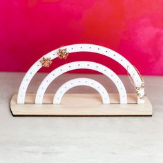 a white wooden stand with two rings on it and a pink wall in the background