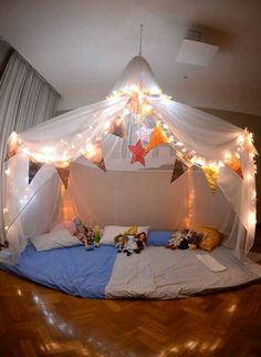 a bed that has some lights on the headboard and canopy over it in a room with wood floors