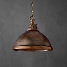 an old fashioned light hanging from a chain on a gray wall with no one in it