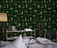 a bedroom with green wallpaper and white bedding in front of a night stand