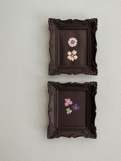 two framed pictures on the wall with flowers in them, one is brown and the other is white