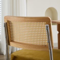 a close up of a chair with a wooden back and metal frame, in front of a window