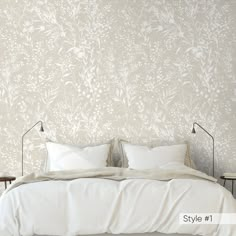 a bed with white sheets and pillows in front of a wallpapered bedroom area