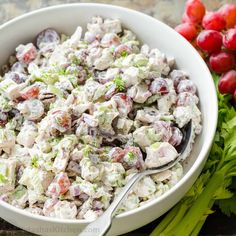 a white bowl filled with salad next to some grapes