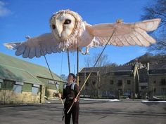 an owl puppet is being held by a man in a black suit and white shirt