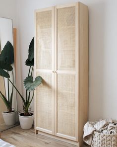 a large wooden cabinet sitting next to a mirror and potted plant in a room