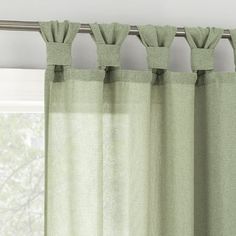 green curtains hanging on a rod in front of a window with white walls and windowsills