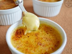 a spoon with some food in it on top of a white bowl filled with pudding