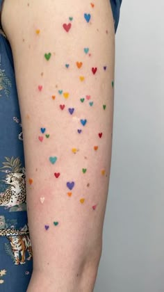 a woman's arm with colorful hearts on it