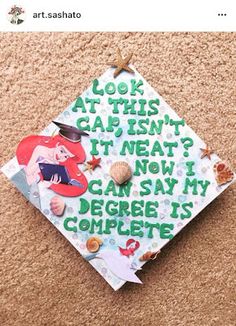 a graduation cap with writing on it sitting on the ground next to a corkscrew