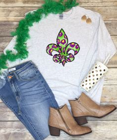 a white shirt with a fleur de lis design on it and some jeans