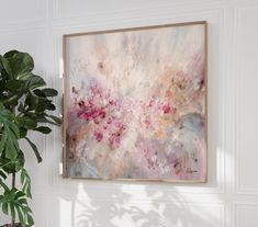 a painting hanging on the wall next to a potted plant in a white room