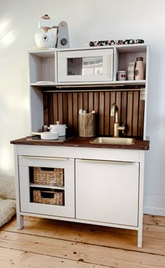 a white cabinet with some baskets on top of it and a microwave in the back