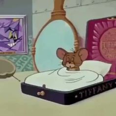 a cartoon mouse laying on top of a bed next to a mirror