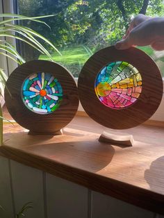 two stained glass plates sitting on top of a window sill next to a potted plant