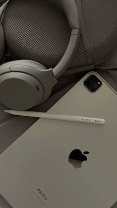 an apple ipad with headphones and a pen next to it on a couch in a living room