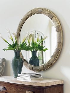 a mirror and vase with flowers on a table