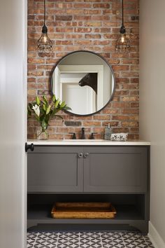 a bathroom with a brick wall and a mirror on the wall, along with a black and white tile floor