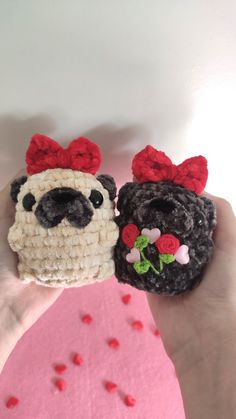 two small crocheted dogs with red bows on their heads, one is black and the other is white