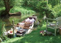 an old boat sitting in the grass next to a wooden bench