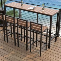 an outdoor table and chairs on a deck overlooking the ocean