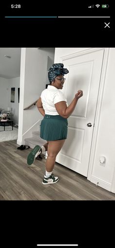 a woman standing in front of a white door wearing green tennis shoes and a skirt