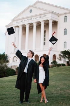 a man and woman in graduation gowns holding up their hats while standing on the grass