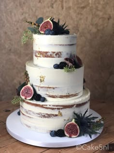 a three tiered cake with figs and berries on top