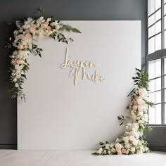 a white backdrop with flowers and greenery on it