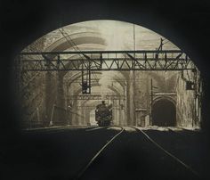 an old photo of a train coming out of a tunnel