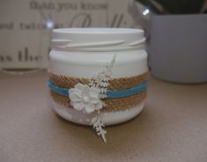 a white mason jar decorated with flowers and burlocks