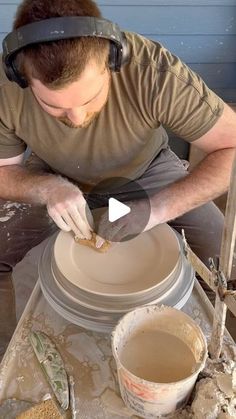 a man is making a vase out of clay with his headphones on and sand in front of him