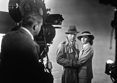 black and white photograph of two men standing in front of a camera with their arms crossed