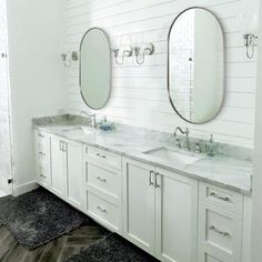 a bathroom with two sinks, mirrors and rugs on the floor in front of them