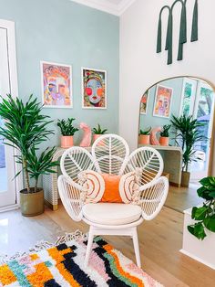 a white chair sitting on top of a wooden floor next to a mirror and potted plants