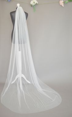 a white veil on top of a mannequin with flowers hanging from the side