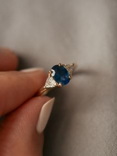 a woman's hand holding an engagement ring with a blue stone